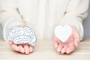 Female hands holding paper cut brain and soul. Conflict between emotions and rational thinking. Balance and equilibrium between mind and heart concept.